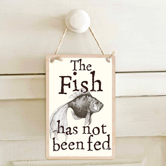 The fish has been fed / The fish has not been fed - Double-sided wooden mini sign.

Made from certified sustainable wood and printed on both sides with a fun, practical message and retro illustration.

15 × 10 cm sustainable wood, natural twine.&nbsp;

Light and durable, eco-friendly, ready to hang.

Made in Suffolk.